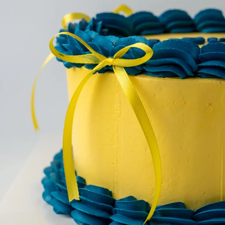 Pastel retro de color amarillo con rosetón y Felicitats en azul de cerca