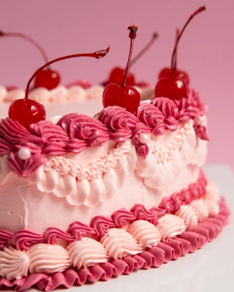 Pastel Corazón Vintage con rosetón rosa y cerezas confitadas de cerca